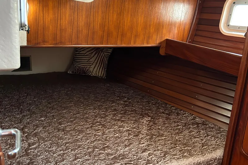 Zephyrus Yacht Photos Pics Cozy cabin interior of 1991 Beneteau 500 Oceanis with wood paneling and patterned bedding.
