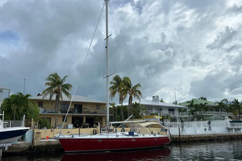 Zephyrus Yacht Photos Pics Red 1991 Beneteau 500 Oceanis sailboat docked near waterfront homes under cloudy skies.