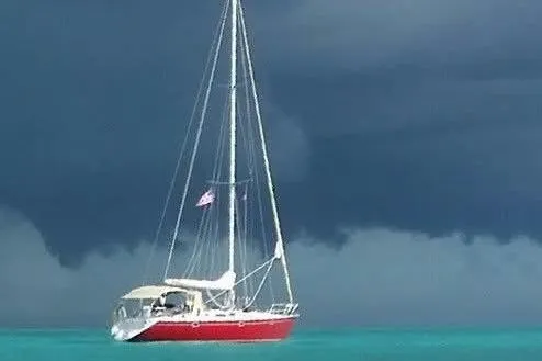 Zephyrus Yacht Photos Pics Sailing yacht Beneteau 500 Oceanis 1991 on turquoise water under stormy sky.