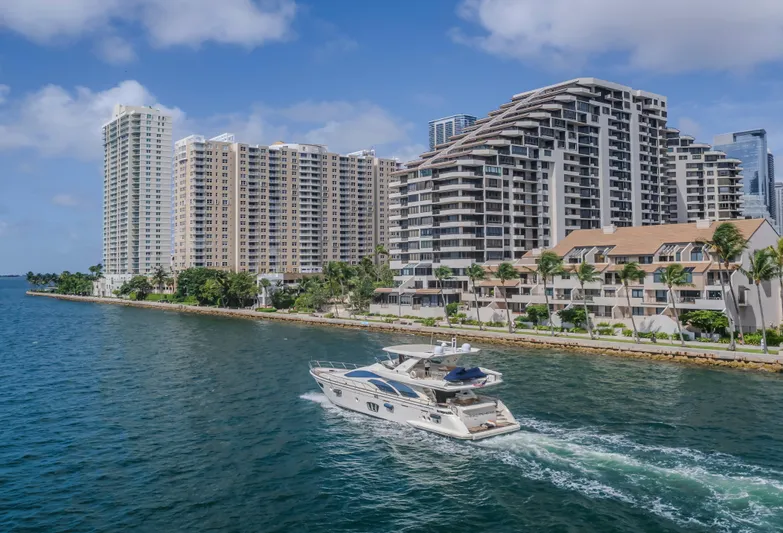 Thinks It's His Too Yacht Photos Pics Azimut Flybridge 2008 yacht cruising near waterfront high-rise buildings under a clear blue sky.