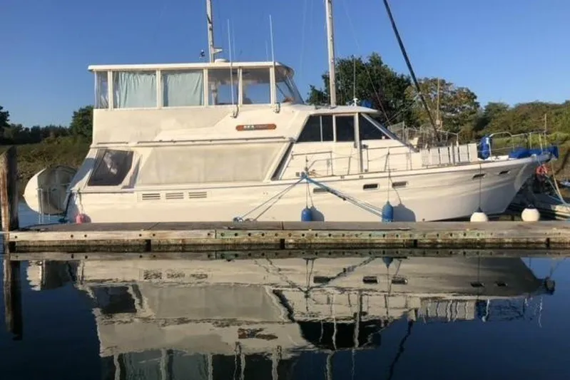  Yacht Photos Pics 1985 Bayliner 4550 Motoryacht docked, reflecting on calm water under clear blue sky.
