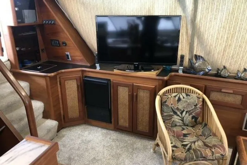  Yacht Photos Pics Interior of 1985 Bayliner 4550 Motoryacht with TV, wicker chair, and wooden cabinetry.