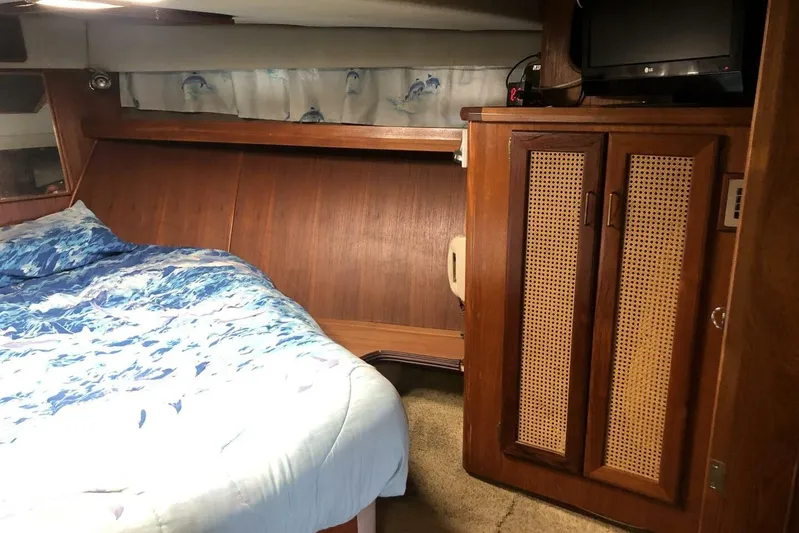  Yacht Photos Pics Cozy cabin interior of 1985 Bayliner 4550 Motoryacht with bed, wooden cabinetry, and TV.