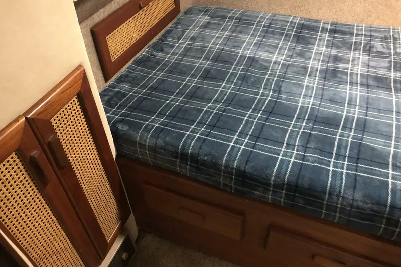  Yacht Photos Pics Interior of 1985 Bayliner 4550 Motoryacht with plaid bedding and wooden cabinetry.