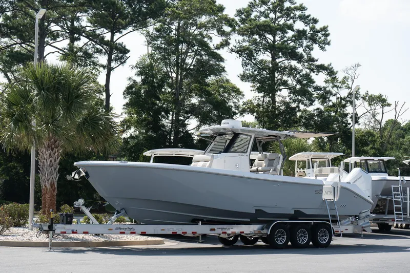 Yacht Photos Pics 2025 Solace 32 CS boat on trailer, surrounded by trees and parked outdoors.