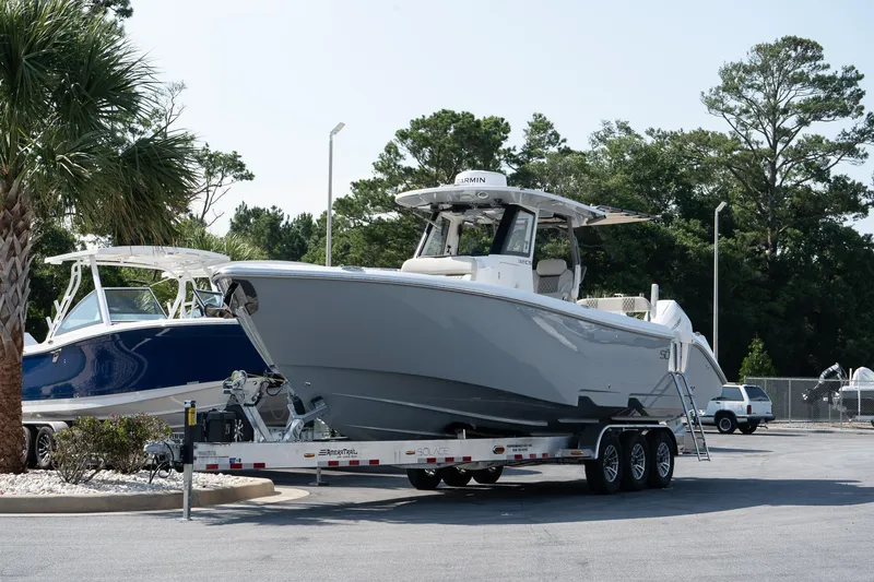  Yacht Photos Pics 2025 Solace 32 CS boat on trailer, parked outdoors near trees and other boats.