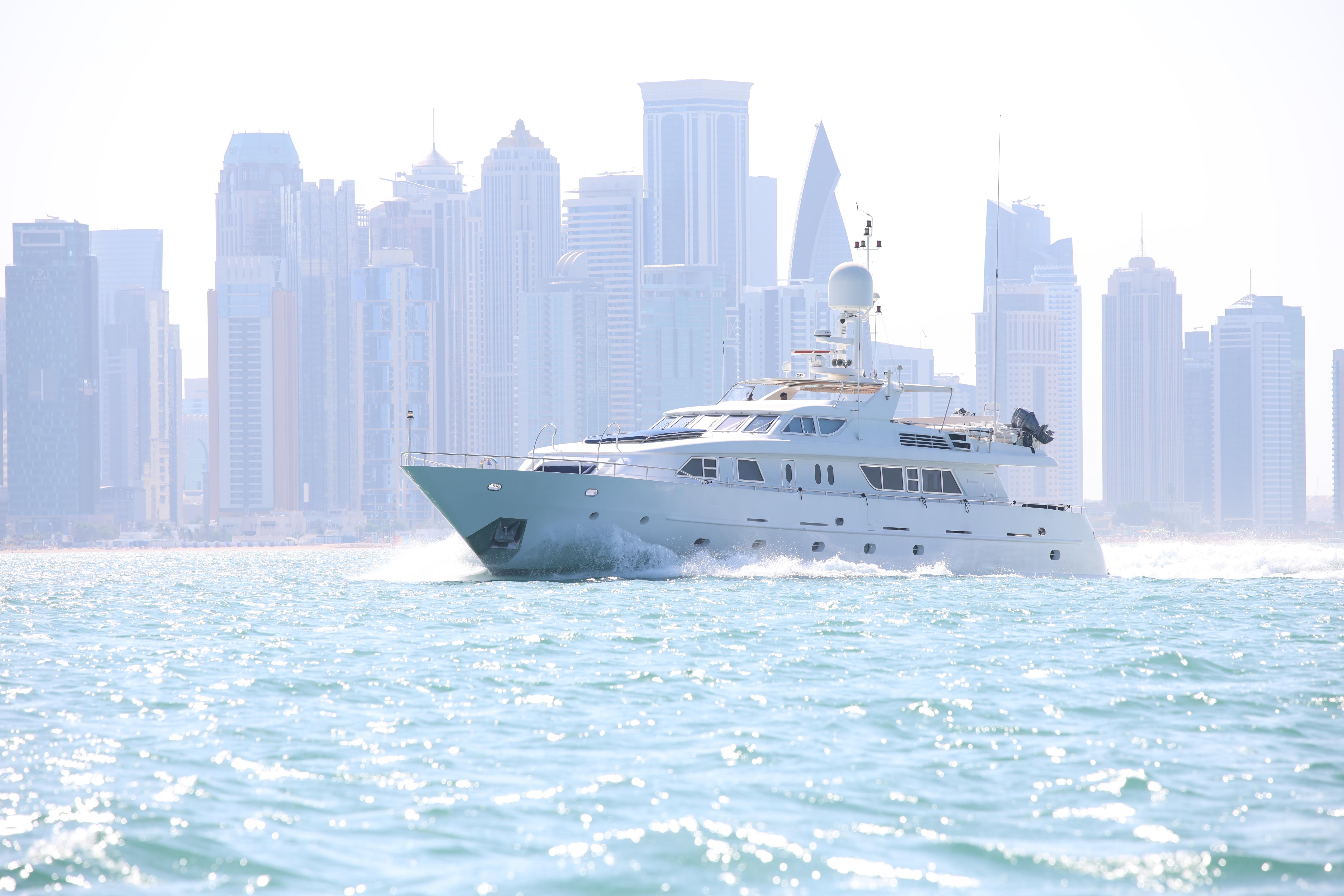 Luxurious Codecasa 105 Custom yacht cruising near a modern city skyline, 1999 model.