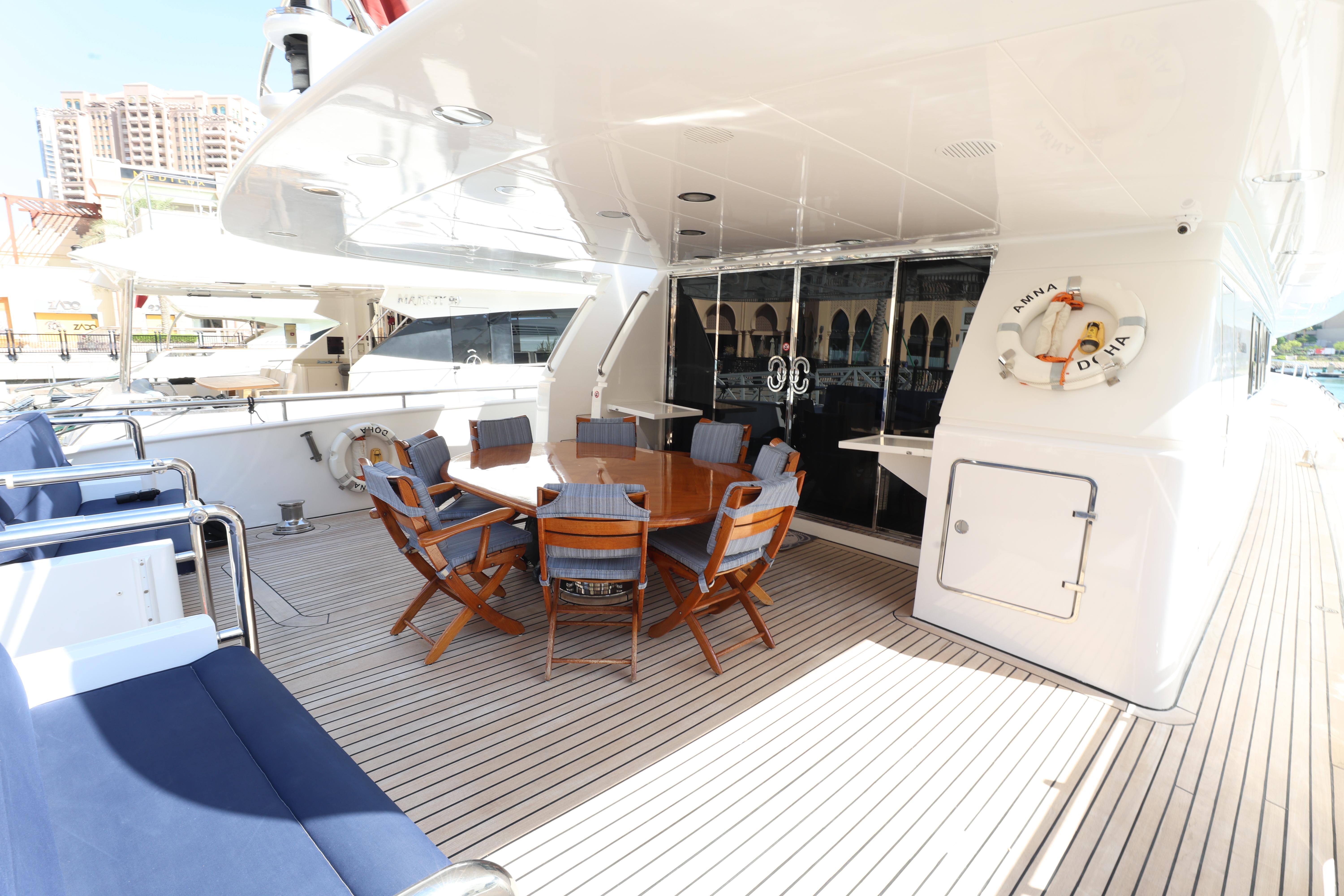 Luxury yacht deck with wooden dining table, blue cushioned chairs, and sleek design, Codecasa 105 Custom 1999.