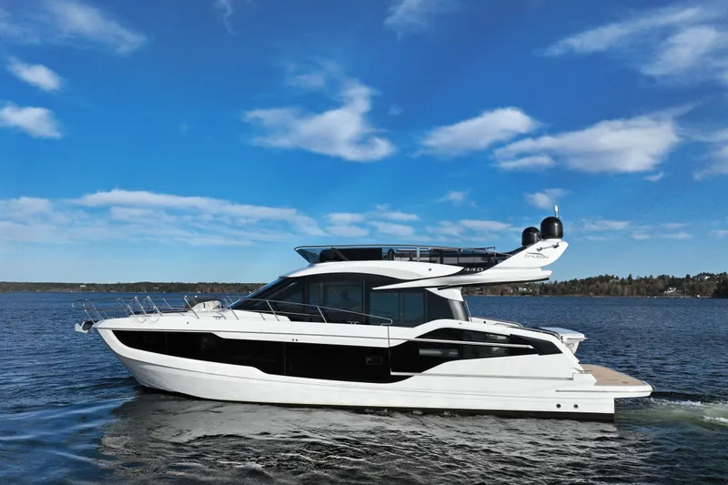  Yacht Photos Pics 2024 Galeon 440 Fly yacht cruising on a serene lake under a clear blue sky.