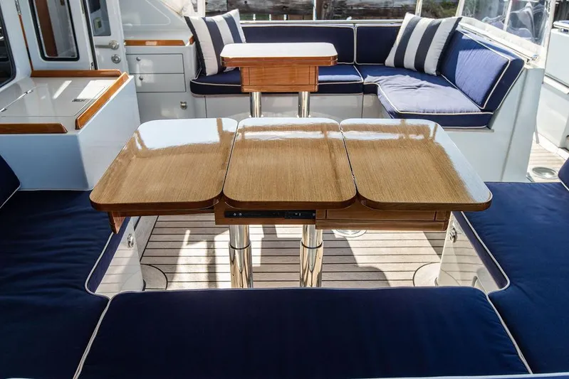 Cabochon Yacht Photos Pics Luxurious 2004 Ta Chiao Custom Pilothouse Cutter interior with elegant wood table and blue seating.