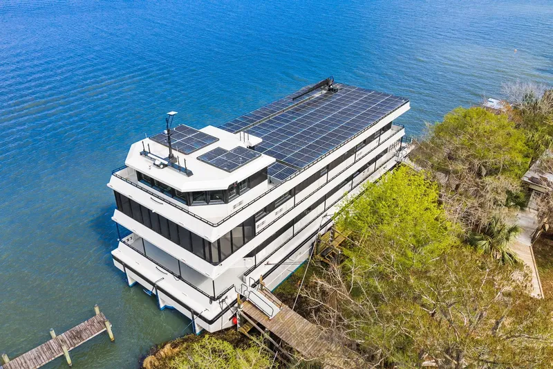 Shine Down Yacht Photos Pics Aerial view of 2025 Breaux Brothers 120 GLV yacht with solar panels docked by the water.