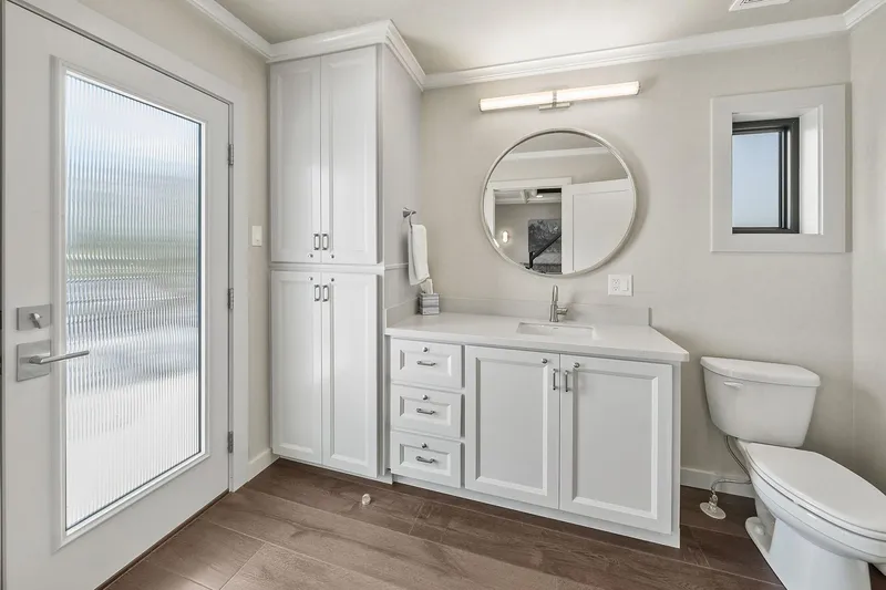 Shine Down Yacht Photos Pics Modern bathroom with white cabinetry, round mirror, and wooden flooring, featuring Breaux Brothers 120 GLV model.