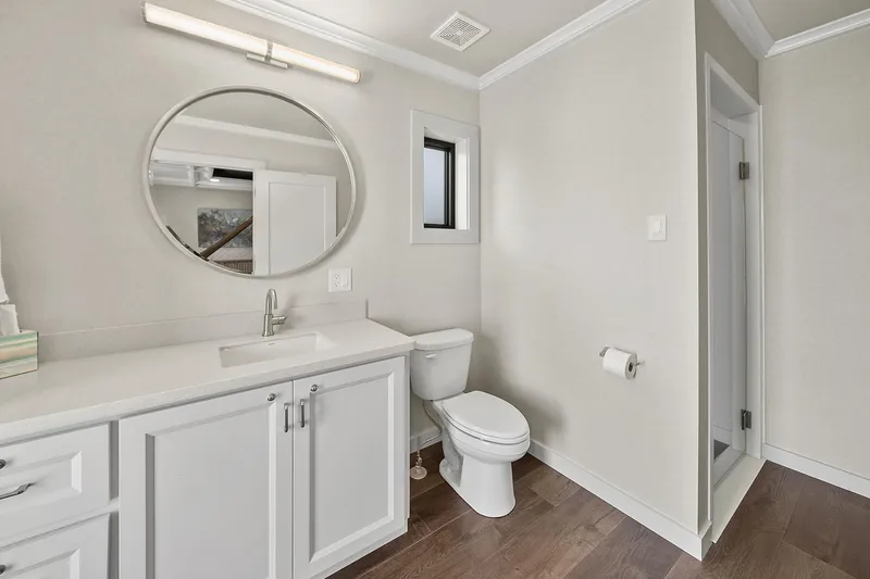 Shine Down Yacht Photos Pics Modern bathroom with white vanity, round mirror, and wooden flooring in Breaux Brothers 120 GLV, 2025.