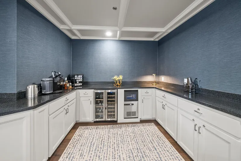 Shine Down Yacht Photos Pics Modern kitchen with white cabinets, blue walls, and a patterned rug, featuring a coffee station.