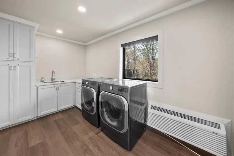 Shine Down Yacht Photos Pics Modern laundry room with sleek appliances, white cabinetry, and a large window view.