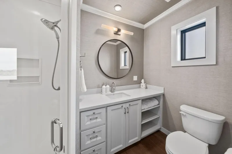 Shine Down Yacht Photos Pics Modern bathroom with round mirror, white vanity, and shower in Breaux Brothers 120 GLV, 2025 model.