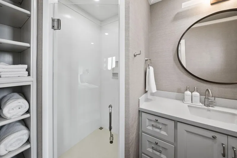Shine Down Yacht Photos Pics Modern bathroom with glass shower, round mirror, and neatly stacked towels on shelves. Breaux Brothers 120 GLV 2025.