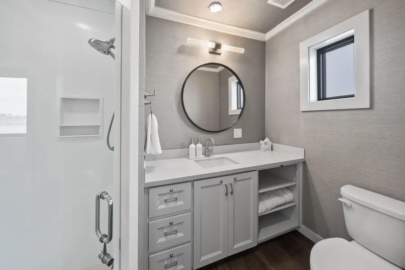 Shine Down Yacht Photos Pics Modern bathroom with round mirror, sleek vanity, and glass shower in Breaux Brothers 120 GLV, 2025 model.