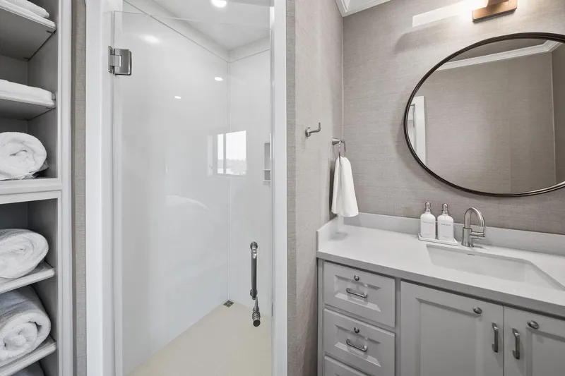 Shine Down Yacht Photos Pics Modern bathroom with glass shower, round mirror, and neatly stacked towels, aboard Breaux Brothers 120 GLV.