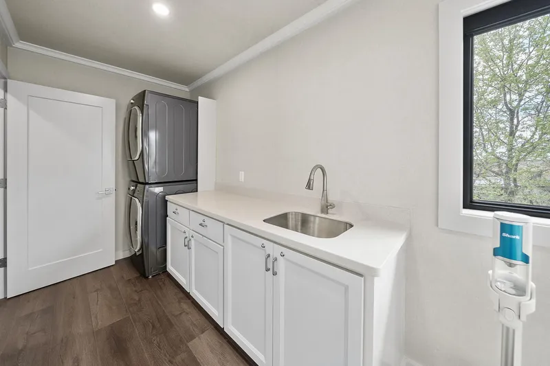 Shine Down Yacht Photos Pics Modern laundry room with stacked washer-dryer, white cabinets, and sink, featuring Breaux Brothers 120 GLV.