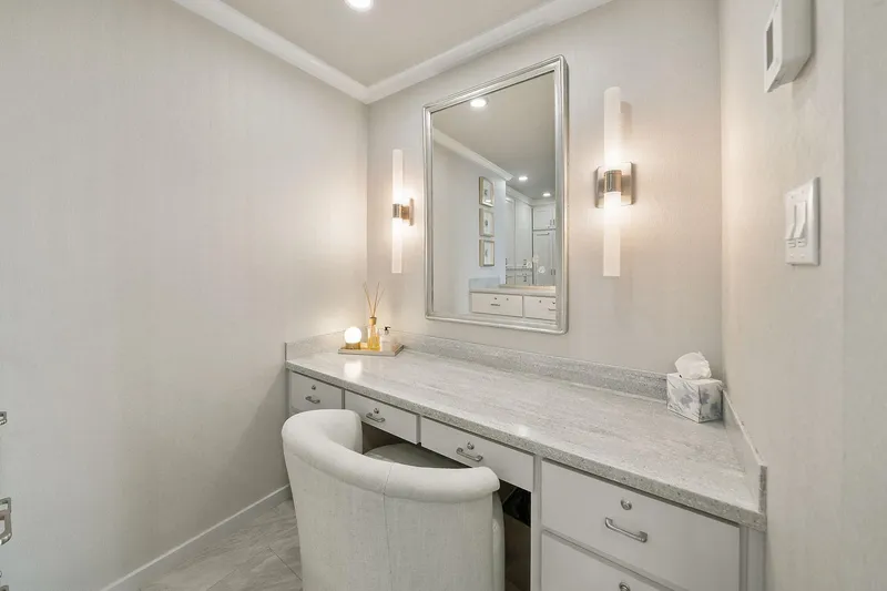 Shine Down Yacht Photos Pics Elegant vanity area with mirror, modern lighting, and plush chair in a neutral-toned room.
