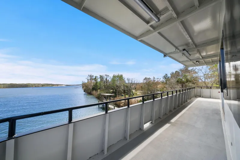 Shine Down Yacht Photos Pics Balcony view from 2025 Breaux Brothers 120 GLV boat overlooking serene river and lush greenery.