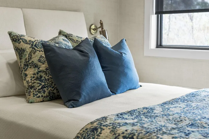 Shine Down Yacht Photos Pics Luxurious bedroom with blue patterned pillows and a cozy bedspread, featuring a modern window view.