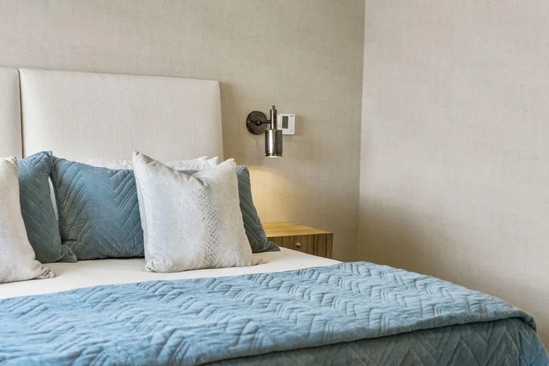 Shine Down Yacht Photos Pics Modern bedroom with blue bedding, white pillows, and wall-mounted lamp. Breaux Brothers 120 GLV 2025.