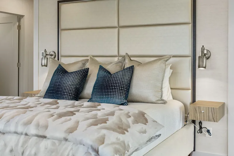 Shine Down Yacht Photos Pics Luxurious bedroom with plush bedding, modern wall sconces, and stylish decorative pillows.