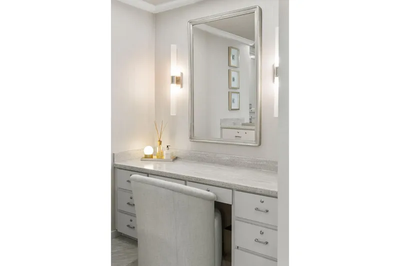Shine Down Yacht Photos Pics Elegant vanity area with large mirror, soft lighting, and plush chair in a modern bathroom.