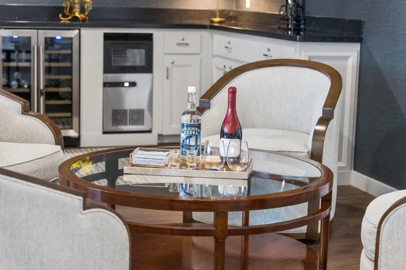 Shine Down Yacht Photos Pics Luxurious lounge with drinks on a glass table, featuring modern cabinetry and appliances.