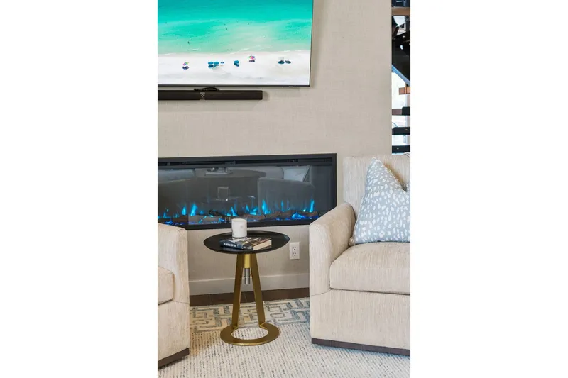 Shine Down Yacht Photos Pics Modern living room with electric fireplace, beach scene TV, and cozy seating.