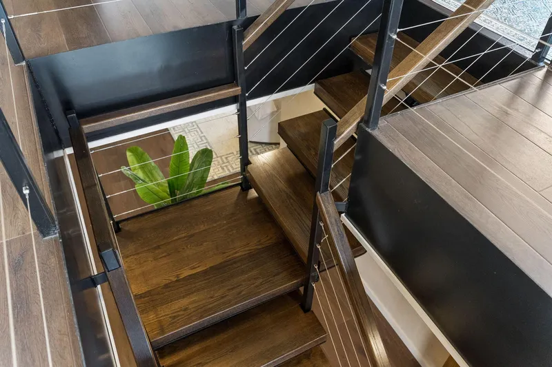 Shine Down Yacht Photos Pics Modern staircase with dark wood steps and metal railings, featuring a plant below. Breaux Brothers 120 GLV 2025.