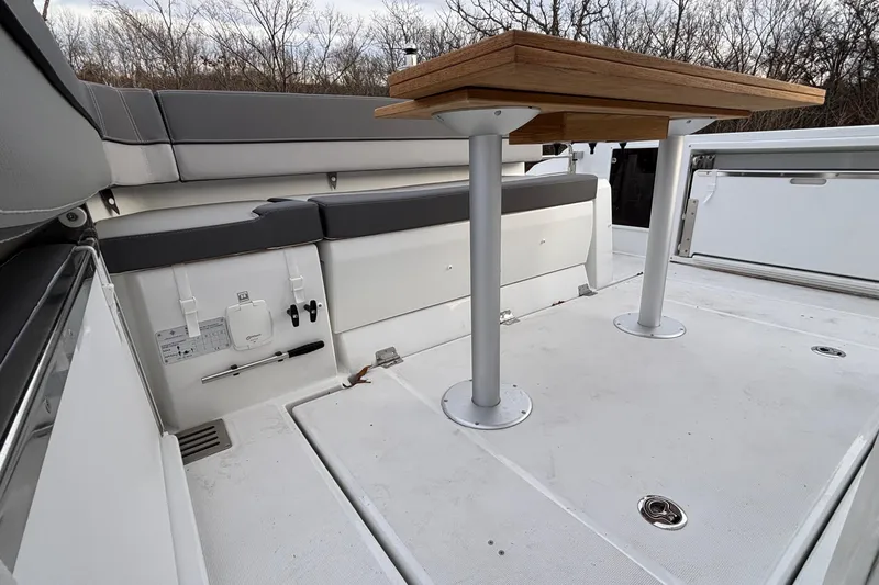  Yacht Photos Pics 2022 Jeanneau Leader 9.0 CC boat interior with wooden table and cushioned seating.