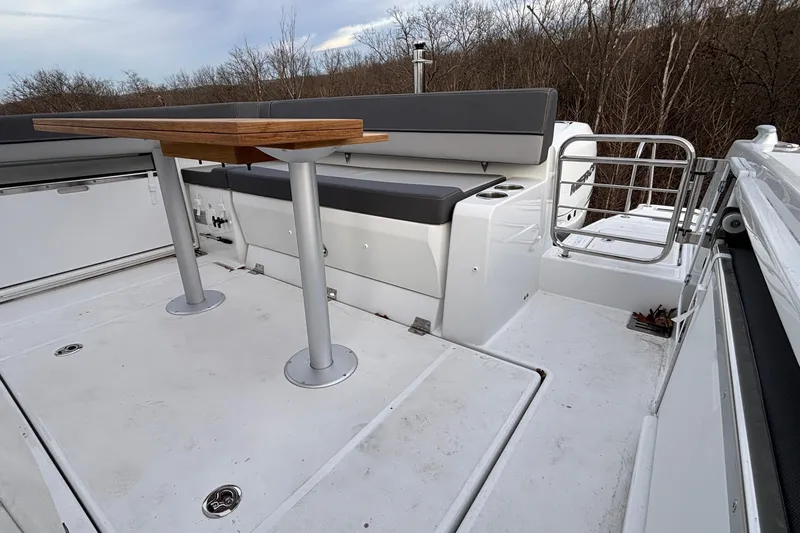  Yacht Photos Pics 2022 Jeanneau Leader 9.0 CC boat deck with seating and table, surrounded by trees.