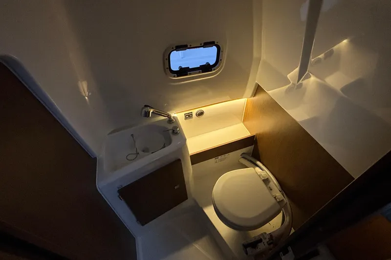  Yacht Photos Pics 2022 Jeanneau Leader 9.0 CC boat bathroom with sink, toilet, and porthole window.