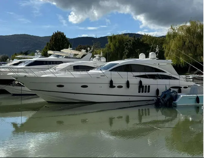  Yacht Photos Pics 2008 Princess V65 yacht docked on calm water, surrounded by lush greenery and mountains.