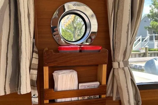 Sea Glass II Yacht Photos Pics 2024 Ranger Tugs R-27 Luxury Edition interior with porthole, striped curtains, and wooden storage.