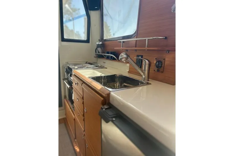 Sea Glass II Yacht Photos Pics 2024 Ranger Tugs R-27 Luxury Edition kitchen with sink, stove, and wooden cabinetry.