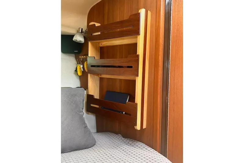 Sea Glass II Yacht Photos Pics 2024 Ranger Tugs R-27 Luxury Edition interior with wooden shelves and cozy bedding.