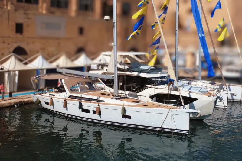 Gr Yacht Photos Pics 2017 Grand Soleil 52LC yacht docked with colorful flags and tents in the background.