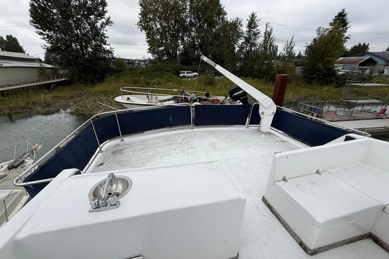 Qui-si-sana Yacht Photos Pics 1989 Jefferson 52 Victory yacht deck with railing and crane, docked near grassy shoreline.