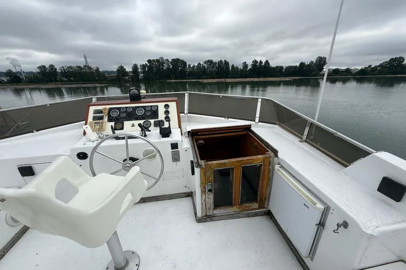 Qui-si-sana Yacht Photos Pics 1989 Jefferson 52 Victory boat helm with steering wheel, controls, and cabin entrance on a calm river.