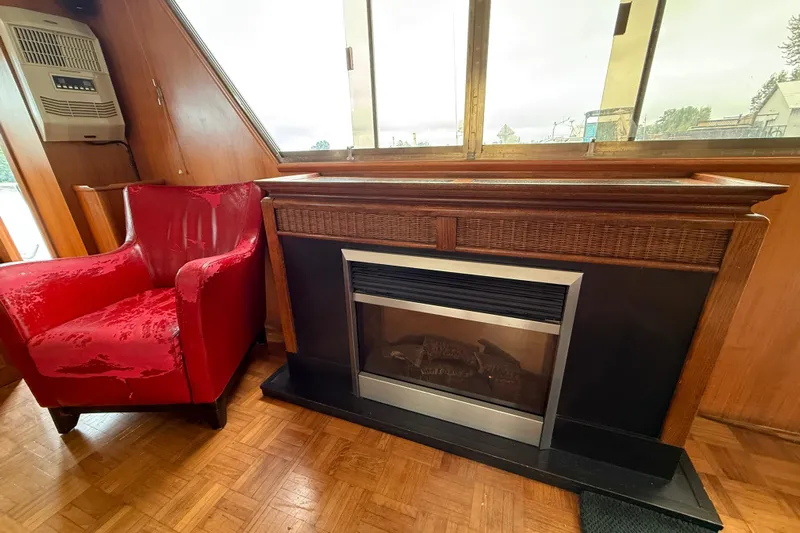 Qui-si-sana Yacht Photos Pics Red armchair and fireplace inside a 1989 Jefferson 52 Victory boat cabin.