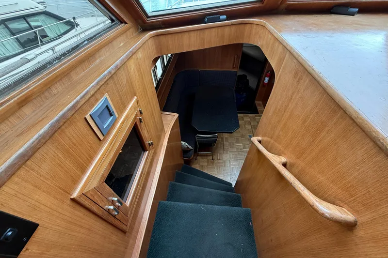 Qui-si-sana Yacht Photos Pics Interior view of 1989 Jefferson 52 Victory yacht, featuring wooden stairs and dining area.