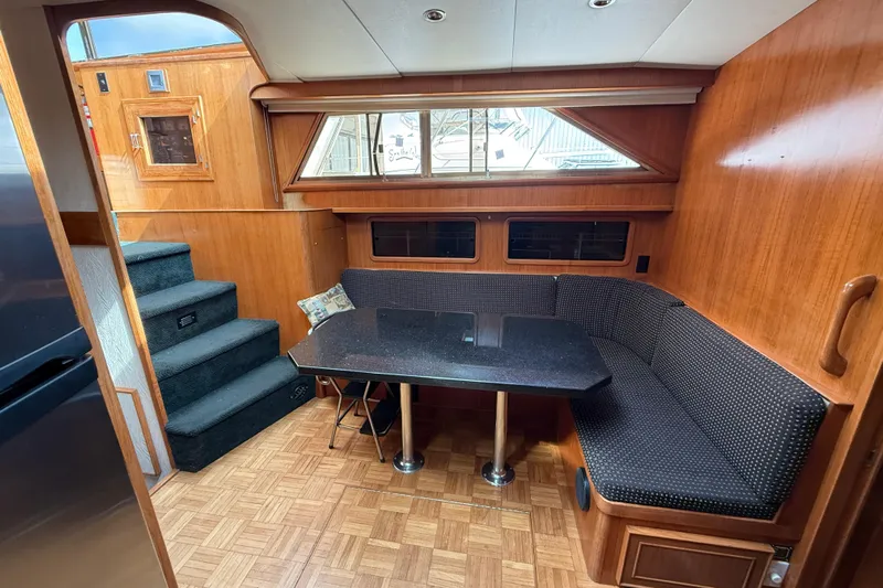 Qui-si-sana Yacht Photos Pics 1989 Jefferson 52 Victory yacht interior with wood paneling, dining area, and stairs.