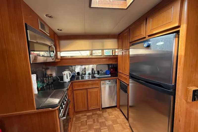 Qui-si-sana Yacht Photos Pics 1989 Jefferson 52 Victory yacht kitchen with wood cabinetry, stainless steel appliances, and parquet flooring.