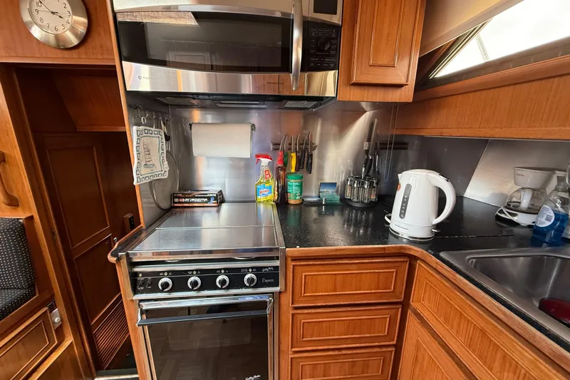 Qui-si-sana Yacht Photos Pics Compact kitchen in 1989 Jefferson 52 Victory yacht with stove, microwave, and kettle.