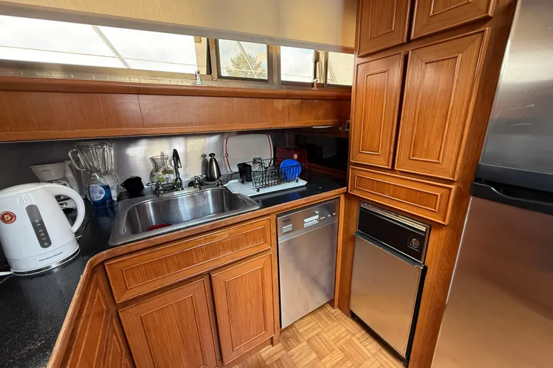 Qui-si-sana Yacht Photos Pics Compact kitchen in 1989 Jefferson 52 Victory yacht with wooden cabinets and stainless steel appliances.