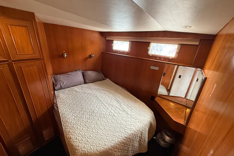 Qui-si-sana Yacht Photos Pics Cozy bedroom in 1989 Jefferson 52 Victory yacht with wood paneling and natural light.